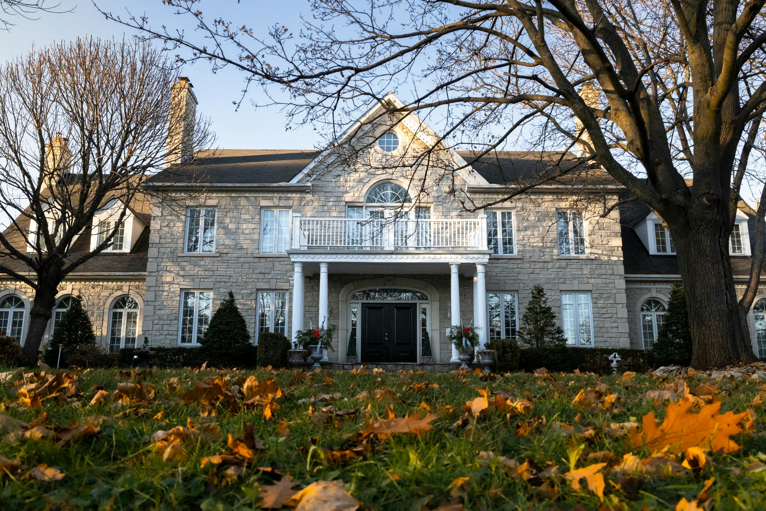 Charming stone house framed by bare trees and autumn leaves.
