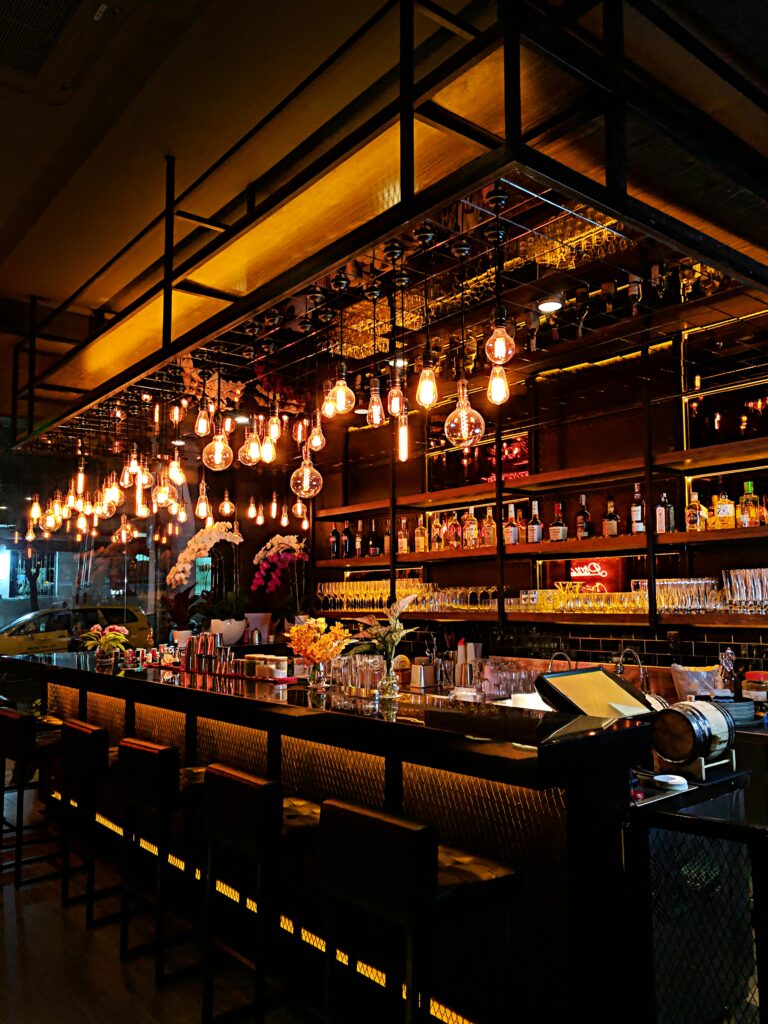 Contemporary bar with warm lighting, showcasing a chic interior with stocked shelves and stylish decor.