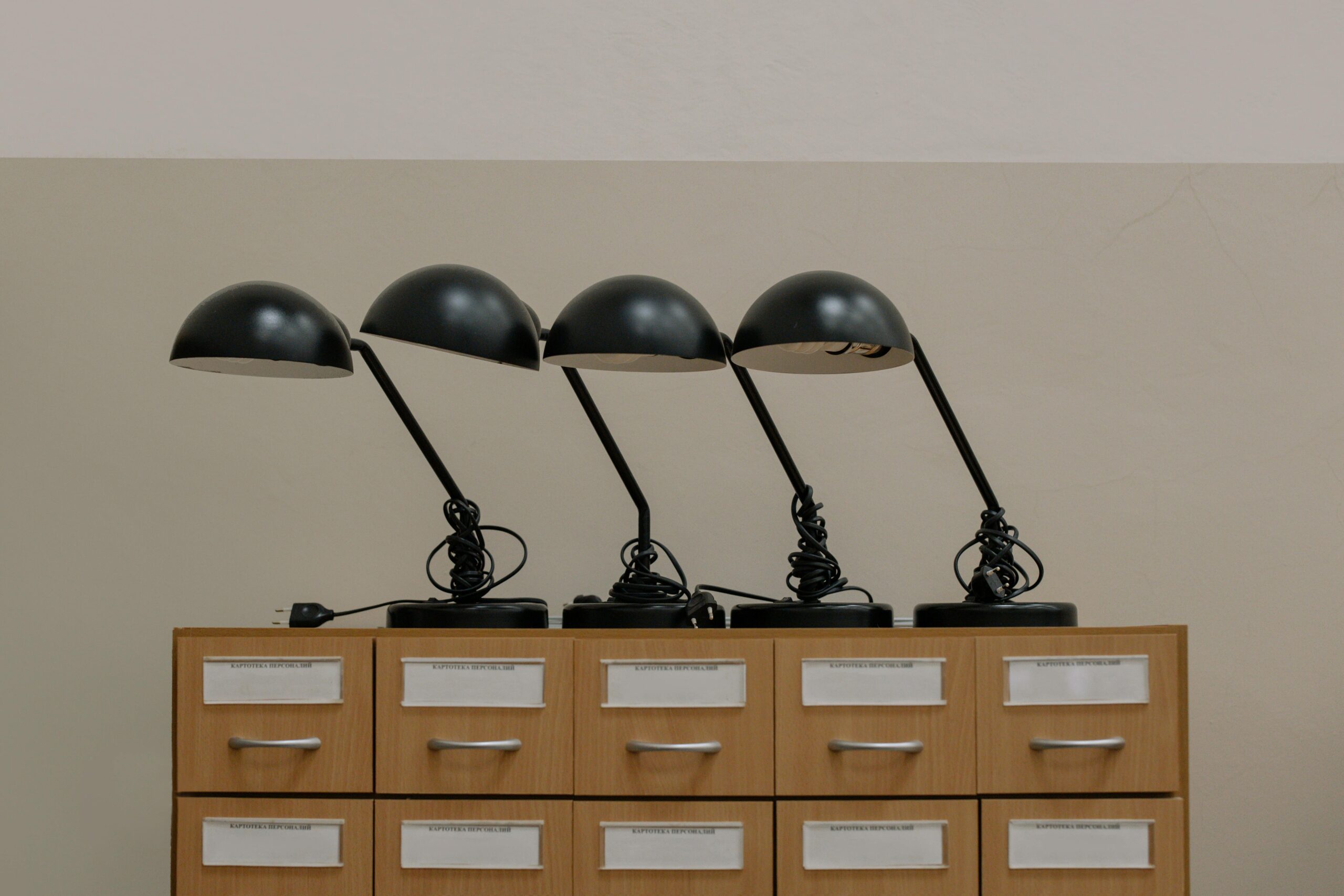 Four black retro desk lamps on a wooden cabinet, embodying minimalist design in an elegant interior.
