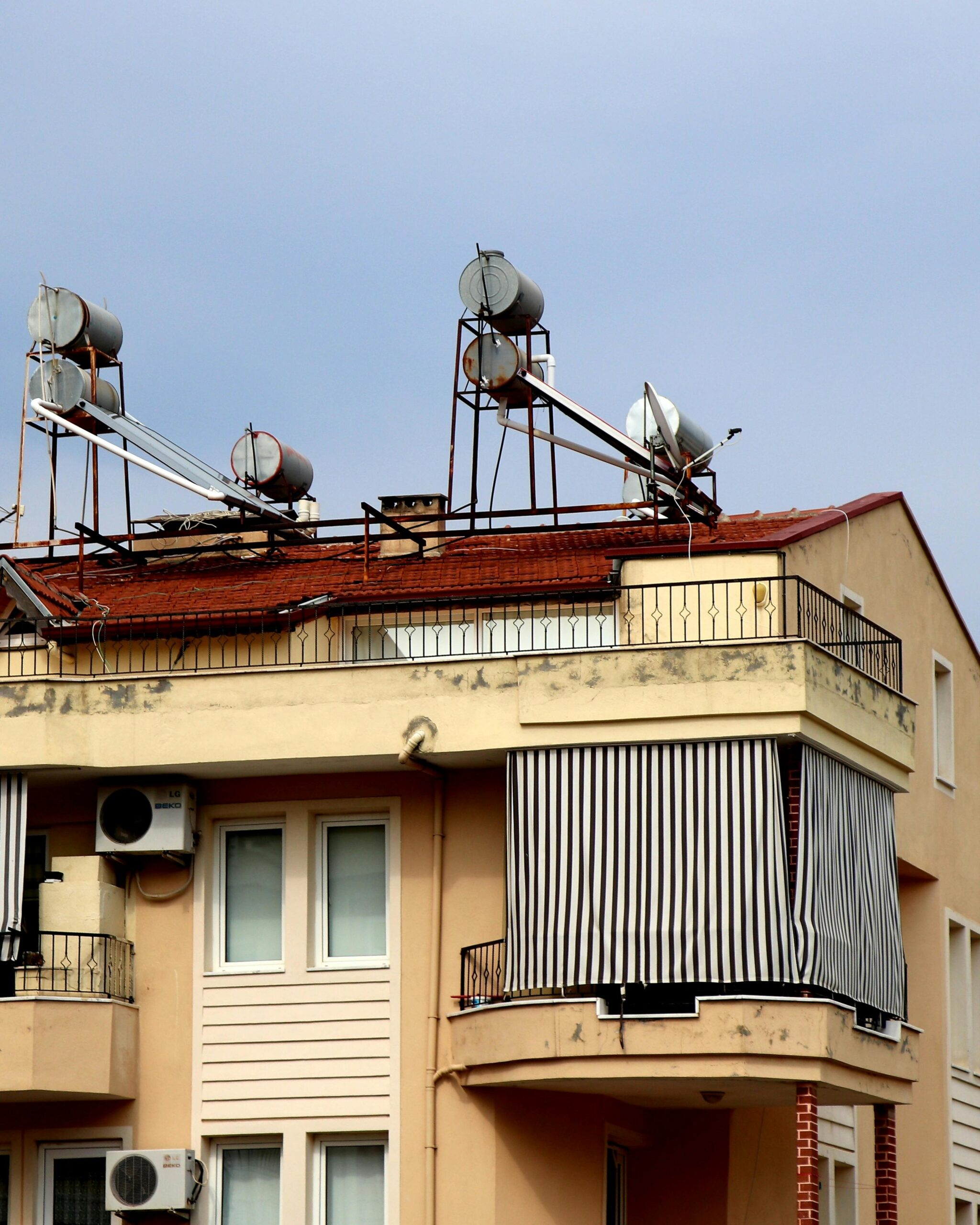 A close-up view of an urban residential building featuring solar water heaters on the rooftop.