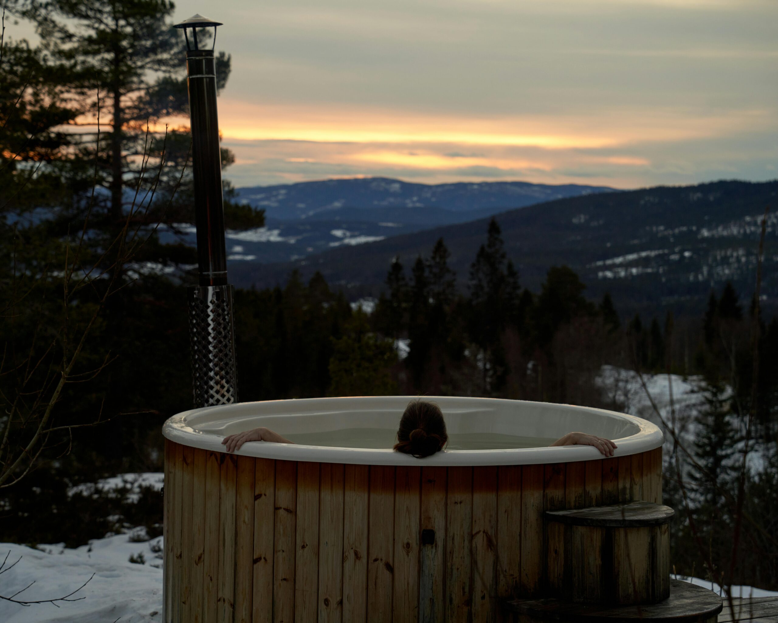 Cozy winter relaxation in a hot tub with stunning Norwegian mountain sunset views in Krøderen, Norway.