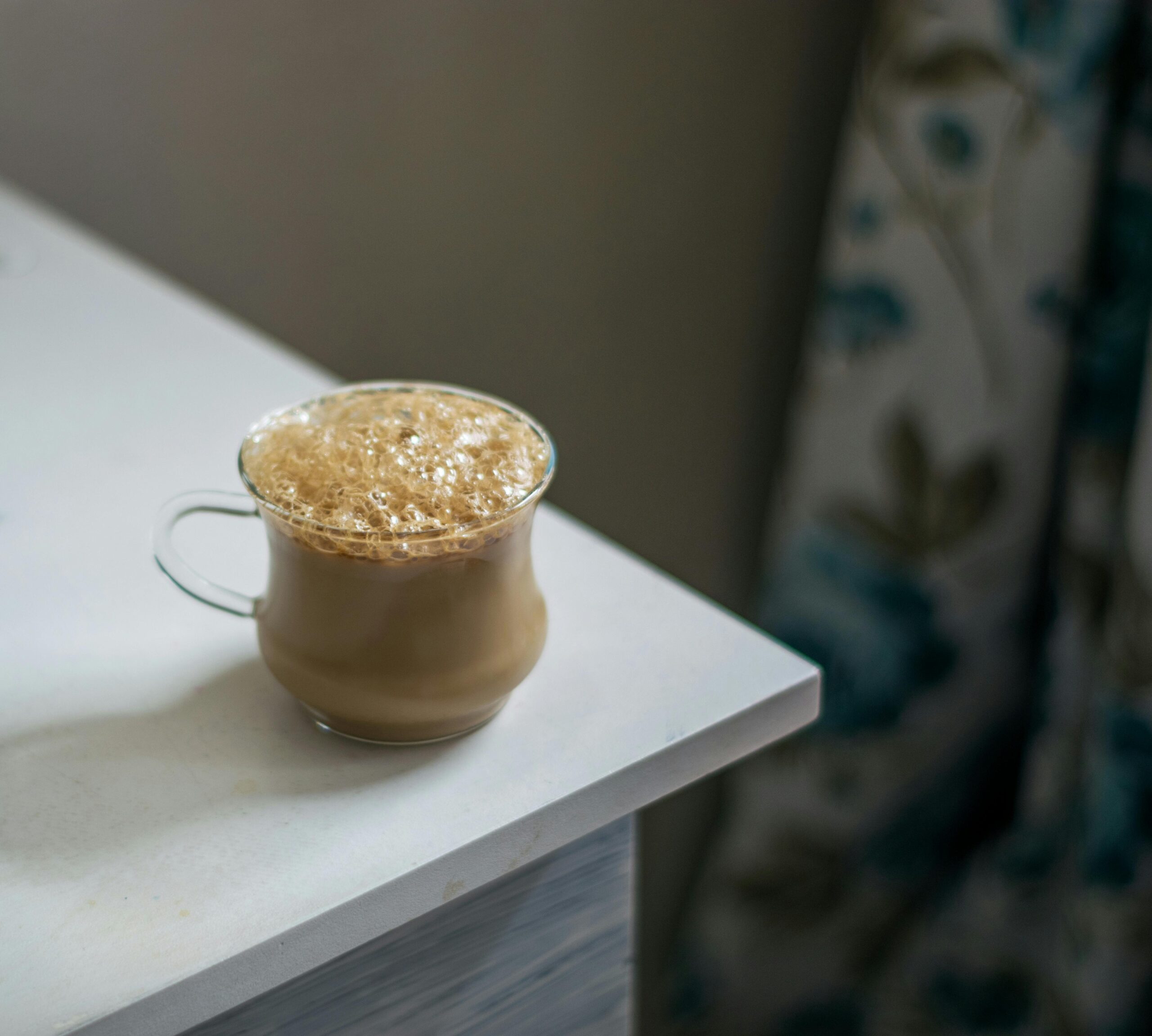 A delicious frothy cappuccino placed on a white table, perfect for coffee lovers.
