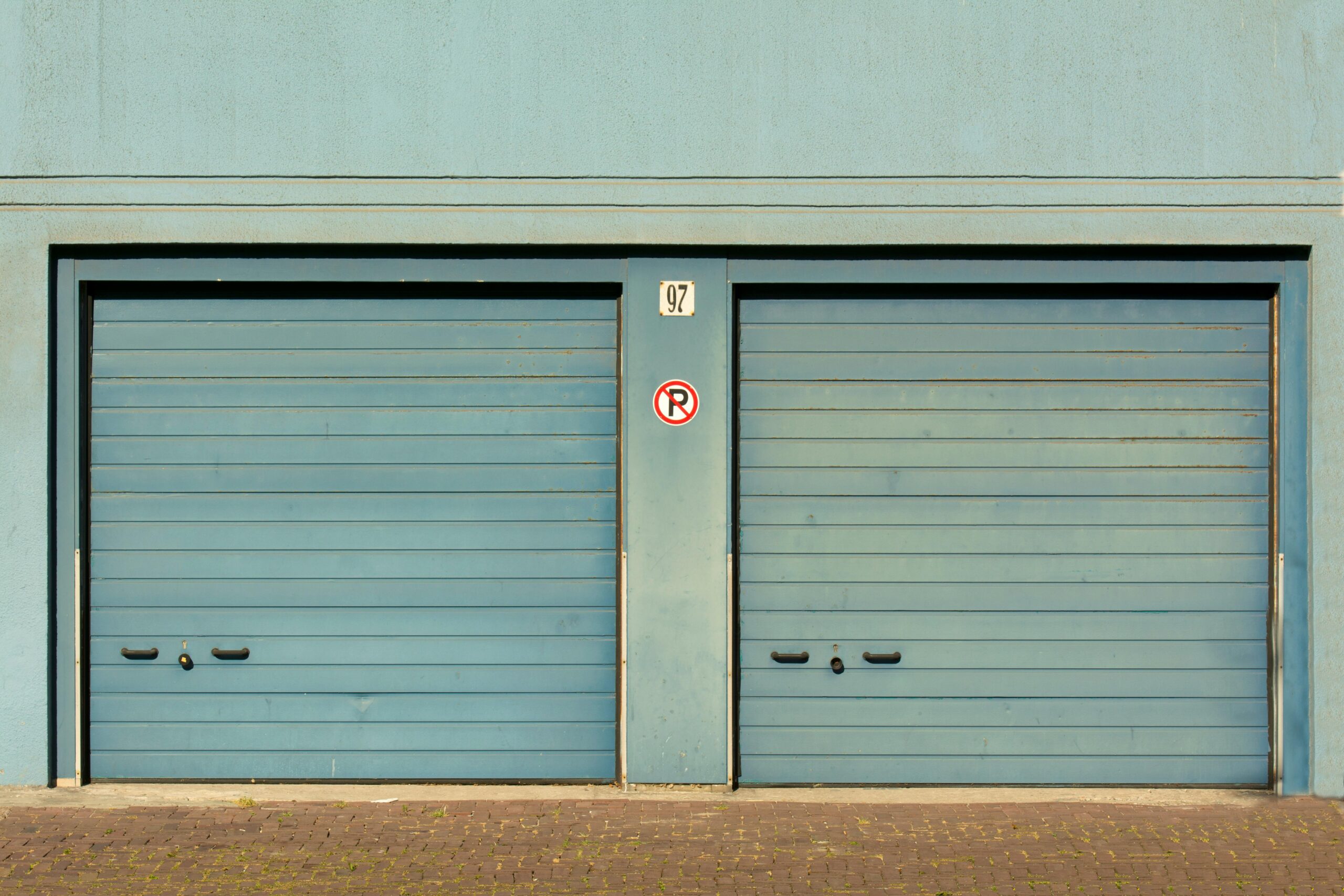 Blue garage doors with a no parking sign painted outdoors.