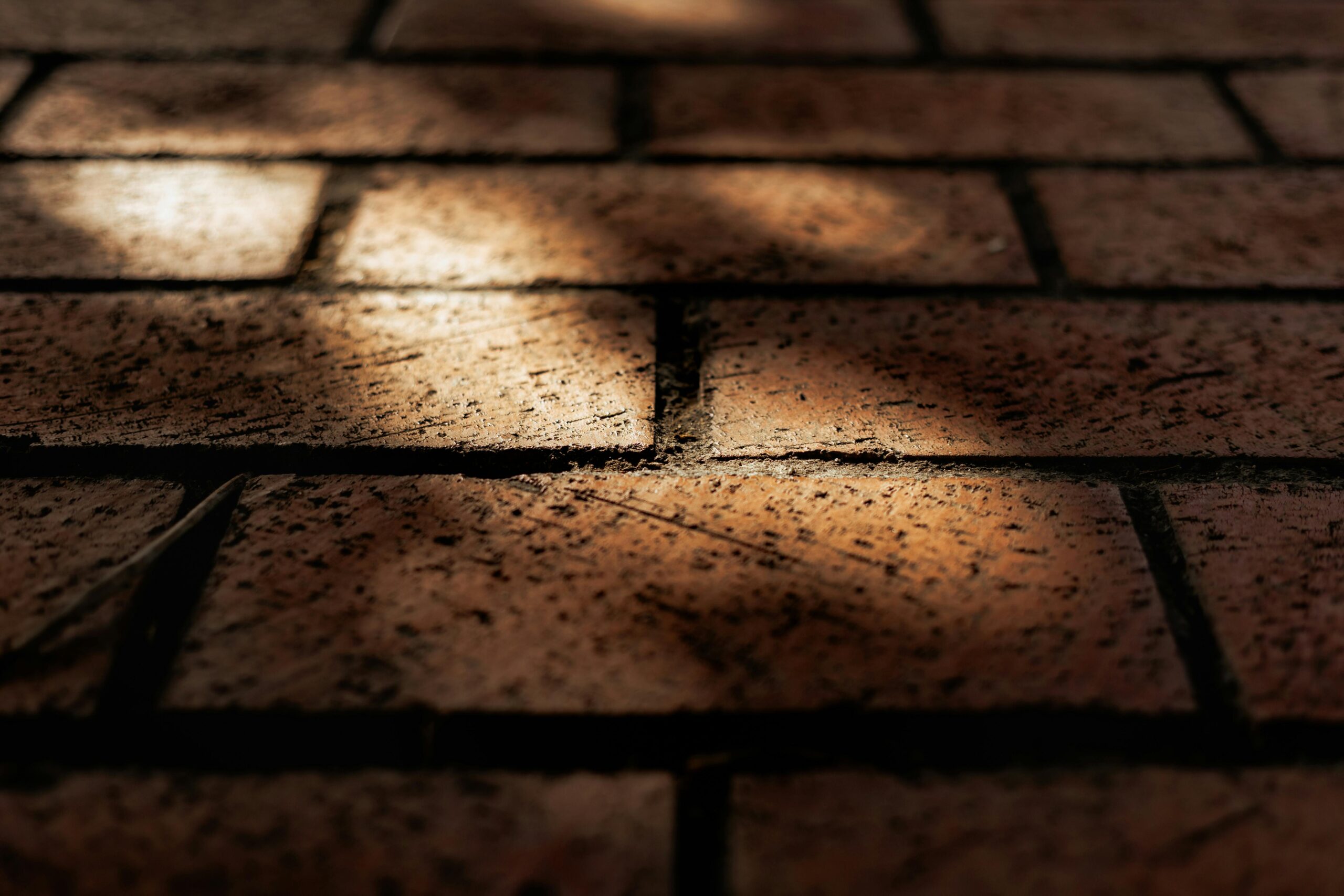 Detailed close-up of textured brick pavement with shadow play highlighting urban patterns.