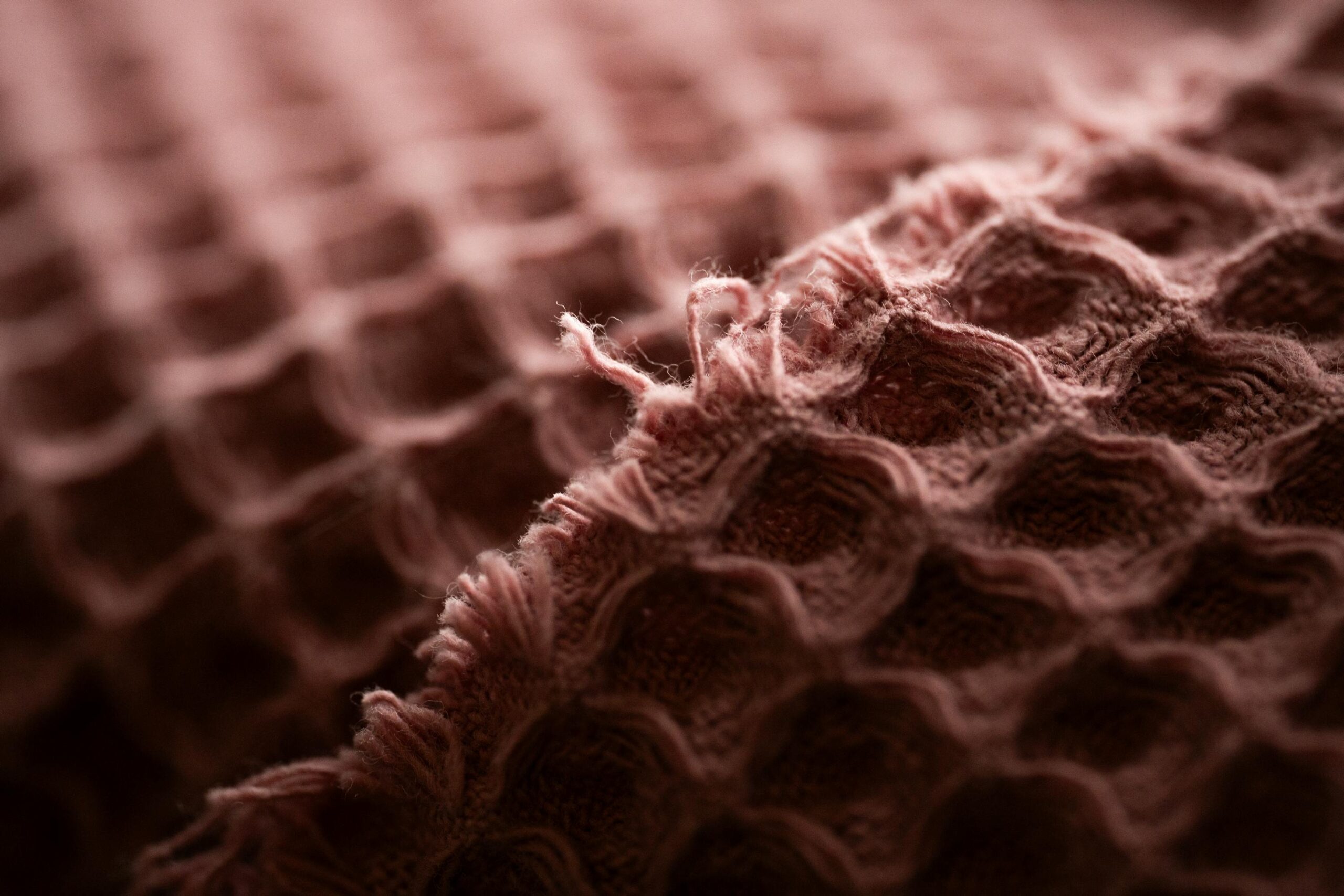 Detailed macro shot of pink textured fabric with soft lighting and visible fibers.