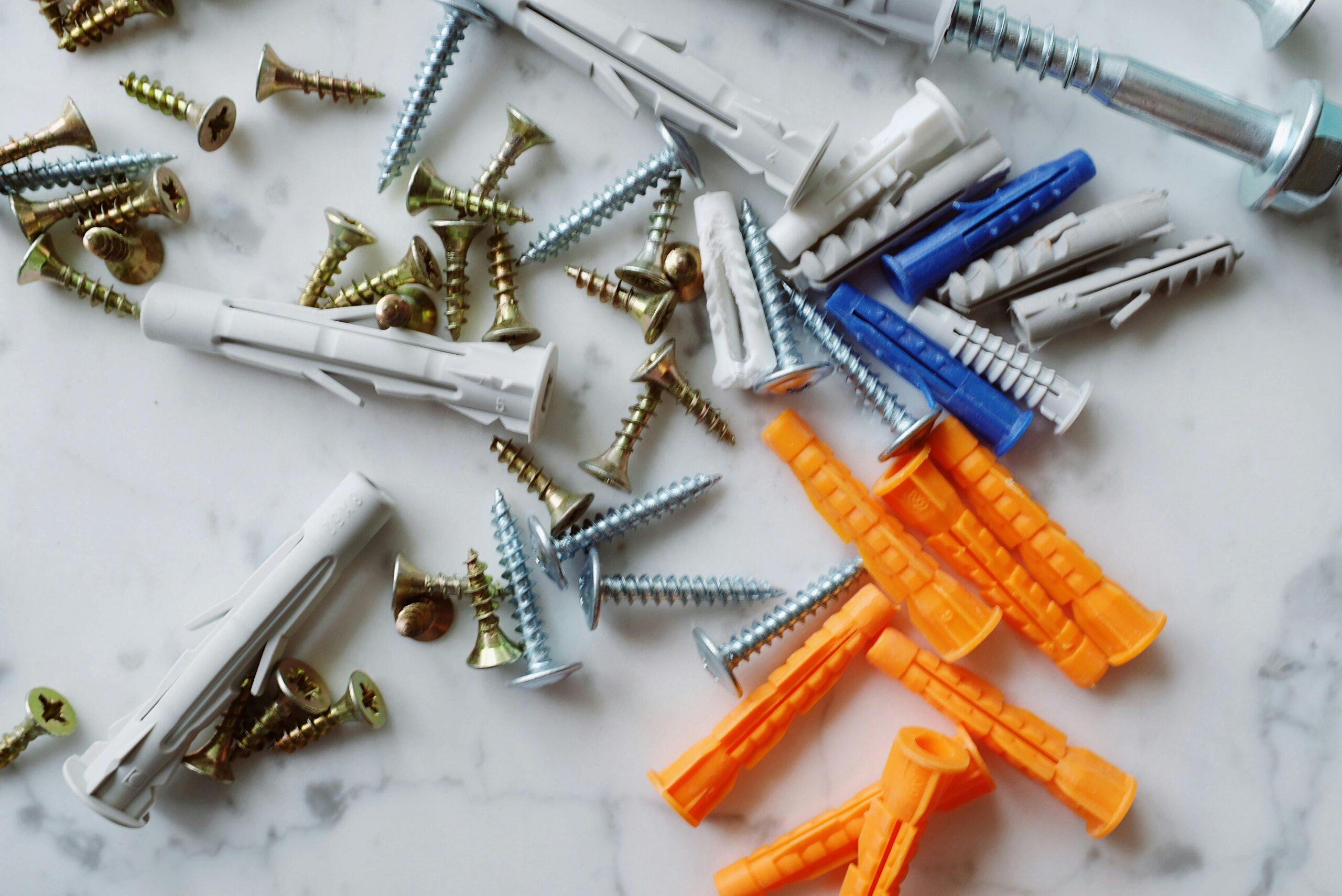 A detailed arrangement of screws and wall anchors on a marble surface, ideal for DIY projects.