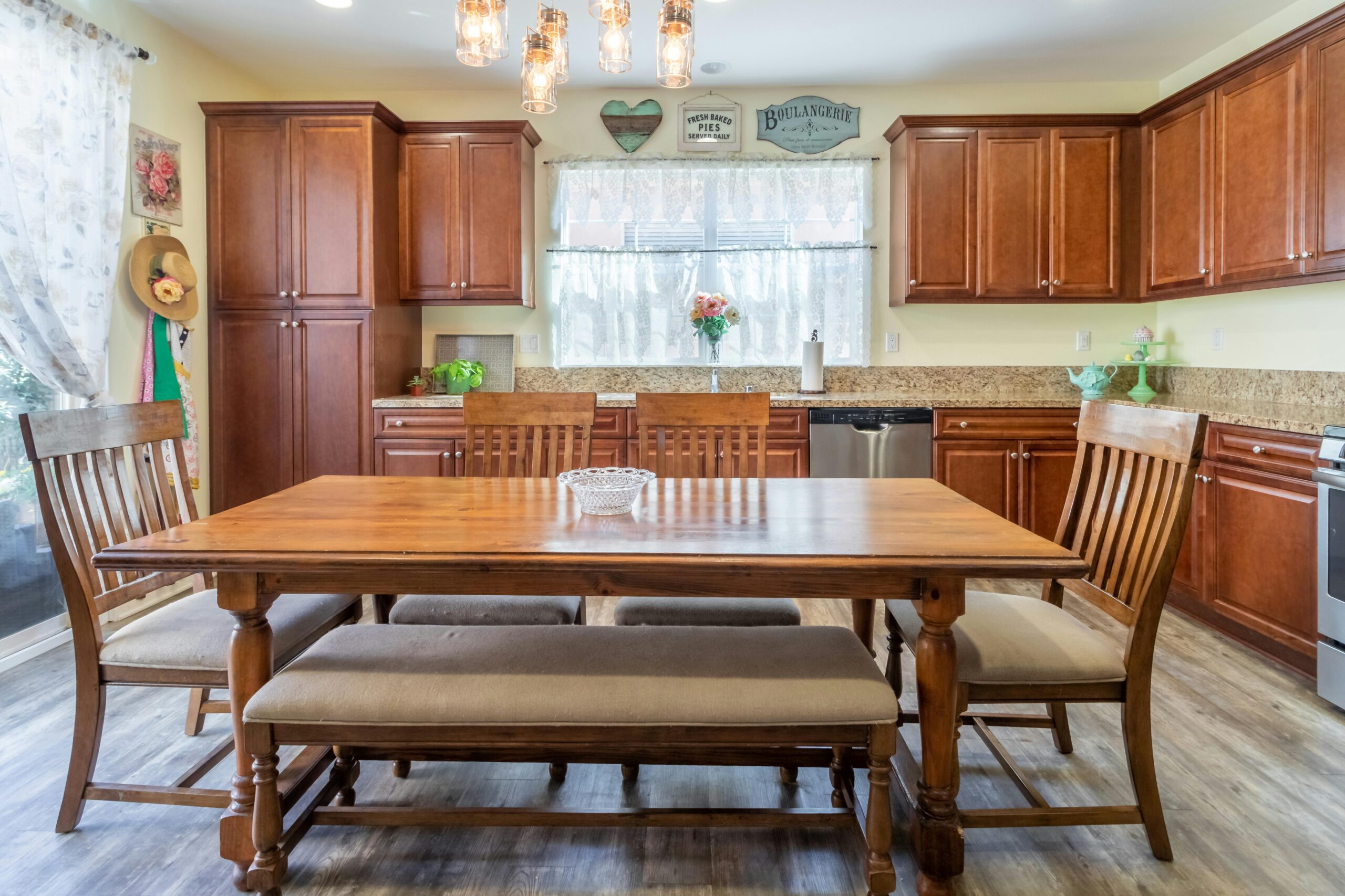 Rustic kitchen with wooden cabinets and dining table, perfect for family gatherings. Cozy feel.
