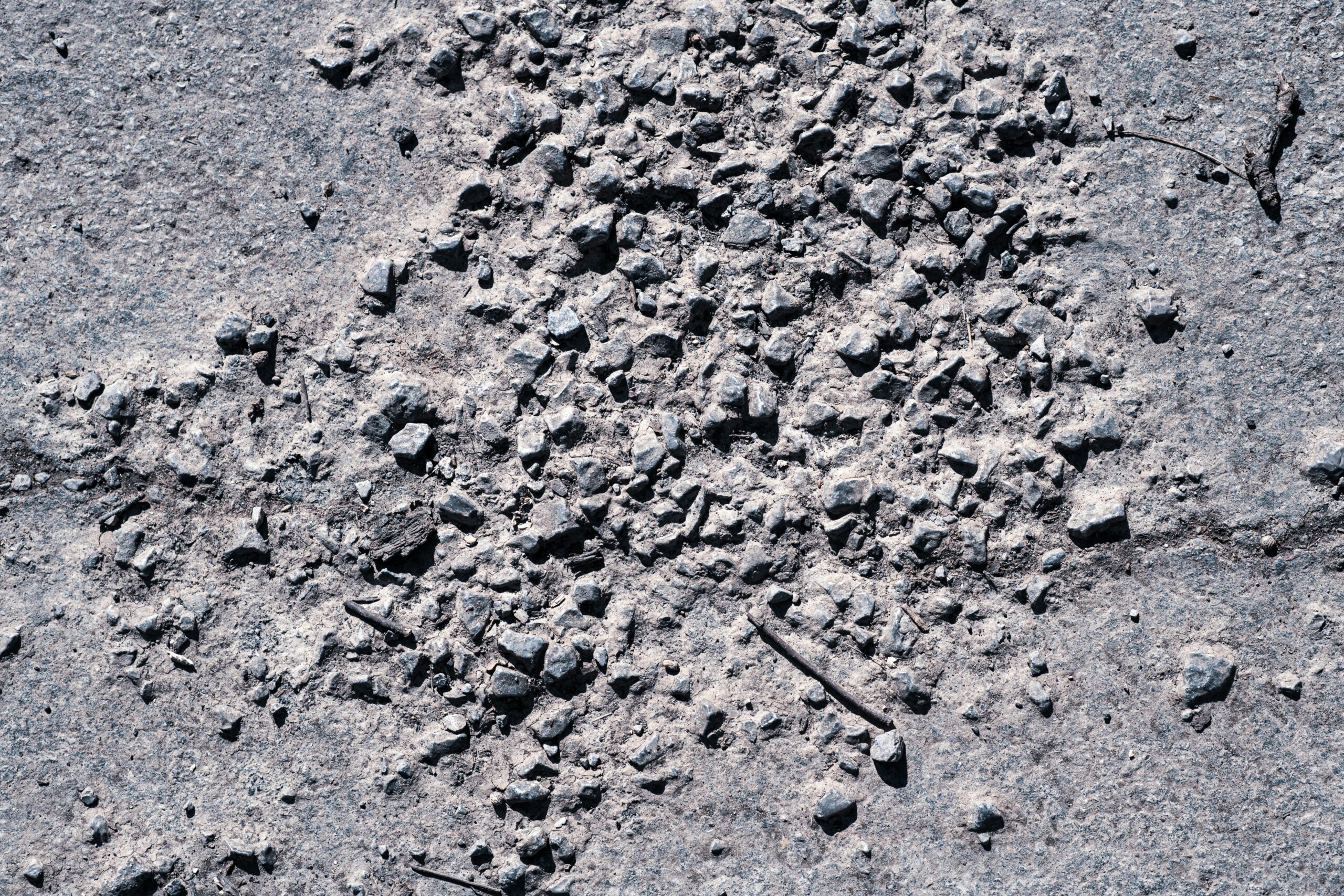 Detailed view of scattered gravel and stones on a rough ground surface, showcasing texture and pattern.