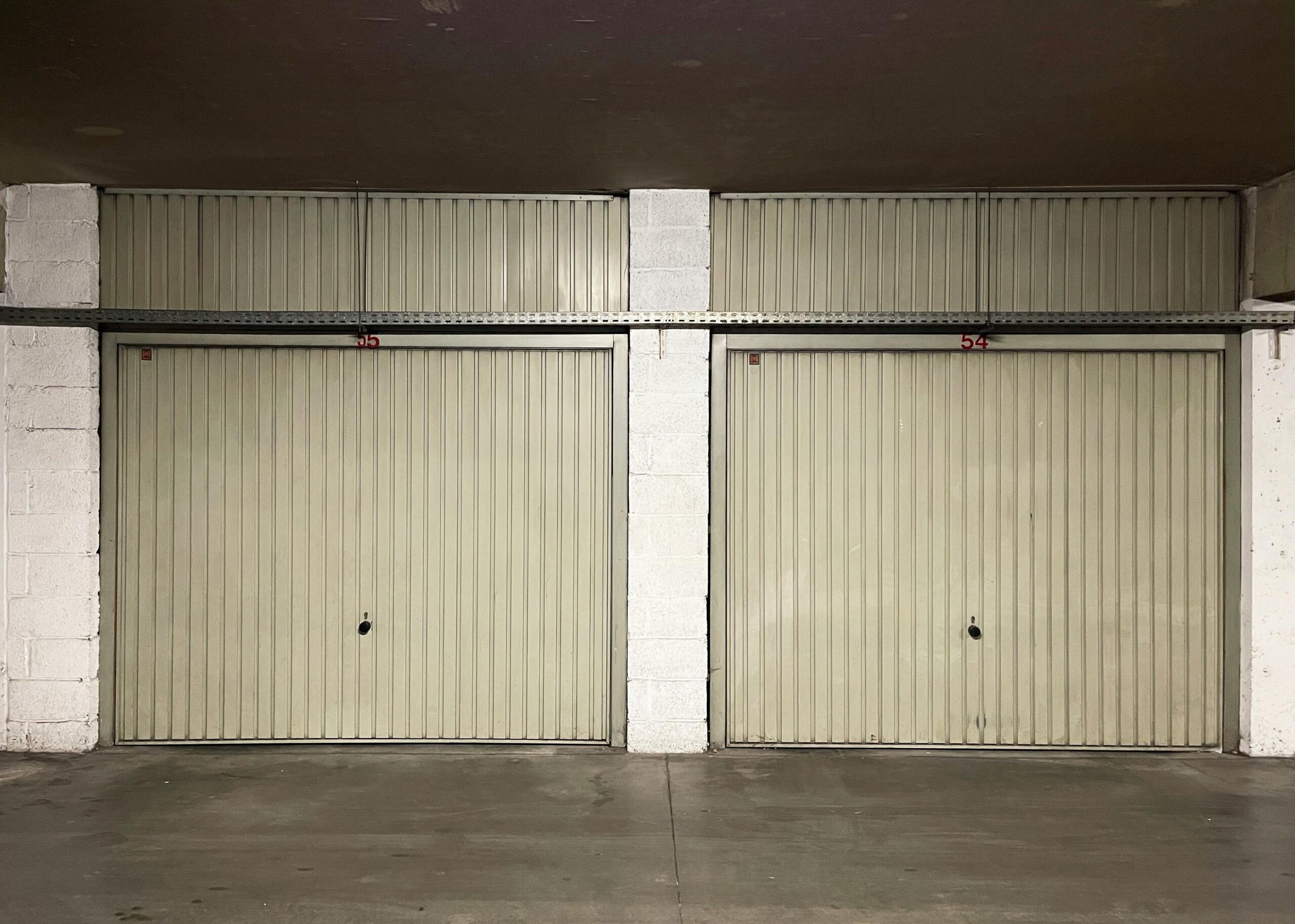 Two closed garage doors inside an empty warehouse space.