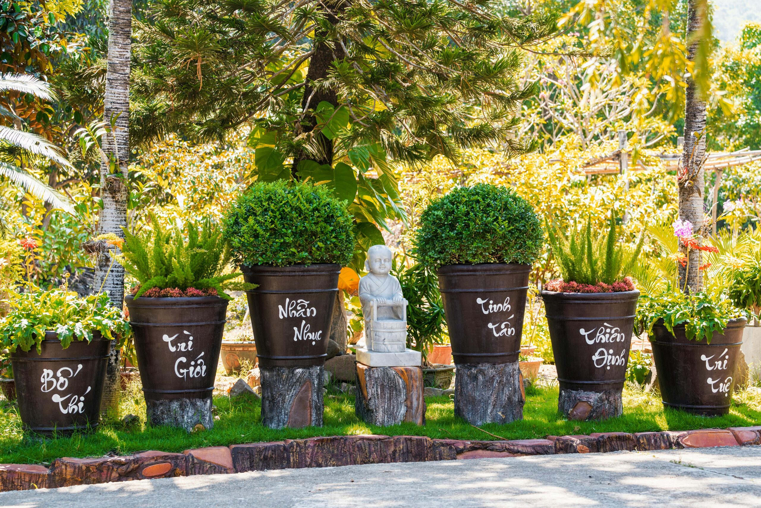 Peaceful outdoor garden scene with potted plants and a small statue under sunny skies.