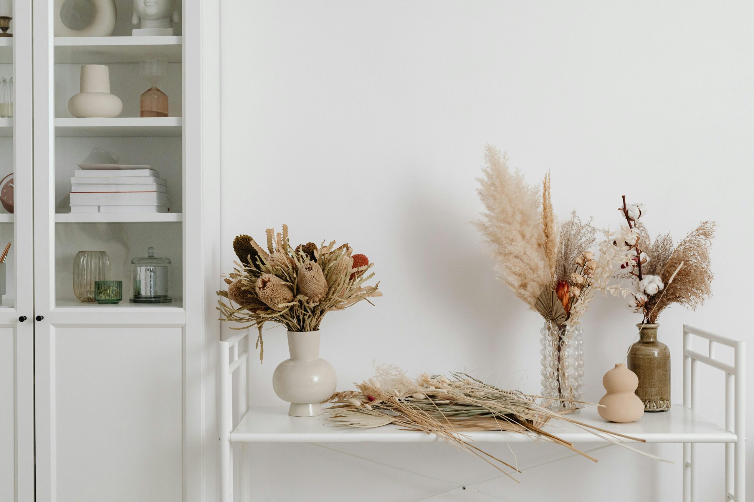 Elegant dried flower arrangements on a white table in a minimalist interior setting.